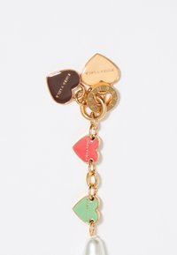 Charm en tono dorado con tres etiquetas en forma de corazón en color marrón, rosa y verde; presenta texto grabado. Un acento de perla completa el diseño.