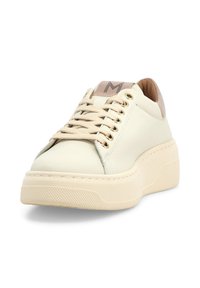 Sneaker beige con suola piattaforma spessa, lacci beige, occhielli dorati e collarino imbottito con logo sulla linguetta, vista frontale inclinata.