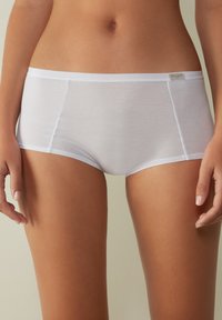 Witte katoenen hipsteronderbroek met een gladde afwerking, elastische tailleband en naadloze randen. Voorzien van een klein metalen label op de tailleband.