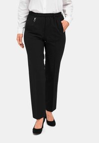 Zwarte rechte broek met een elastische tailleband, zijzakken en een zilveren hardwareaccent. De stof lijkt soepel en licht van gewicht.