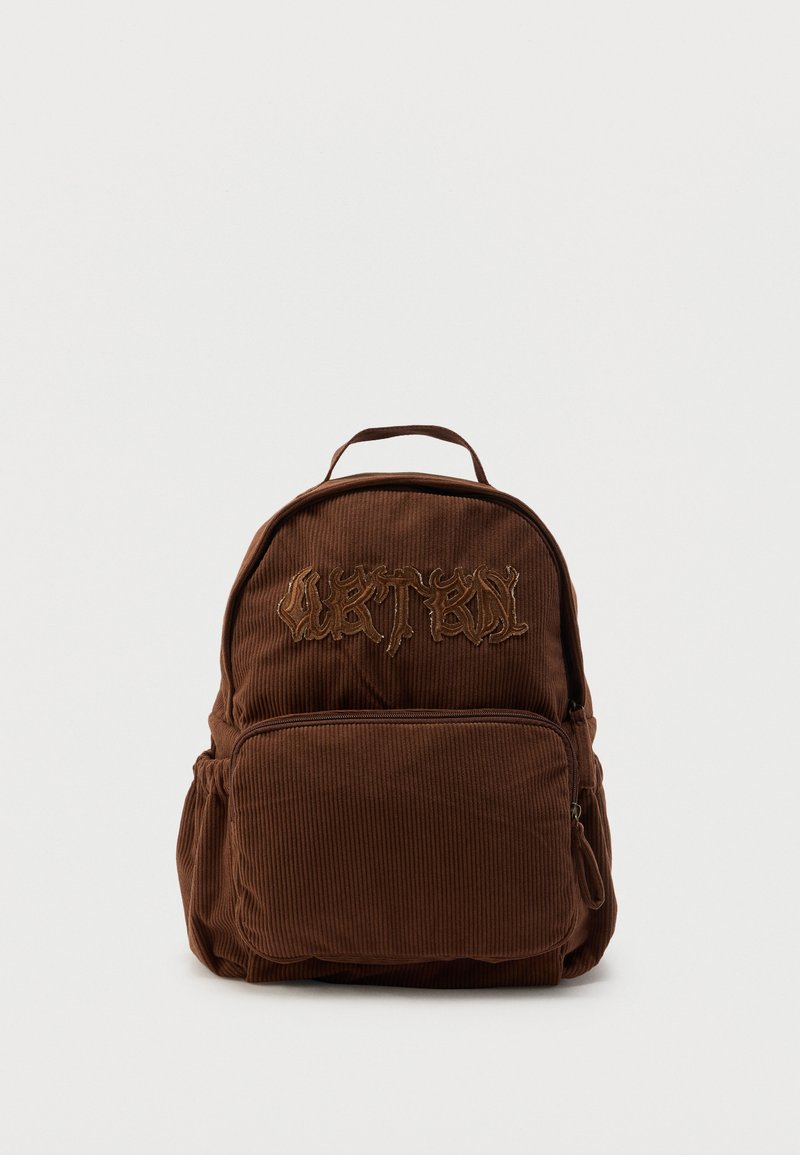 Καφέ σακίδιο από κορδόνι με μπροστινή τσέπη με φερμουάρ και αφηρημένο κεντημένο κείμενο στο πάνω μπροστινό πάνελ, απομονωμένο σε λευκό φόντο.