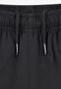 Sorte badeshorts laget av teksturert stoff. Har elastisk midjebånd med snorer og liten Lacoste-logo.