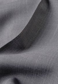 Grau Stoff mit einer glatten, strukturierten Oberfläche. Er weist einen subtilen Glanz und gewebte Muster auf, die sanfte Kurven und Falten zeigen.