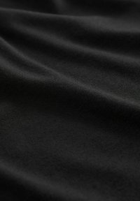 Tissu noir avec une texture lisse et mate, présentant de subtils plis et froissements qui indiquent la douceur et les caractéristiques de tombé.