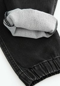 Czarne dżinsy z złożonym jasnoszarym mankietem. Posiadają teksturowaną powierzchnię i elastyczny pas.