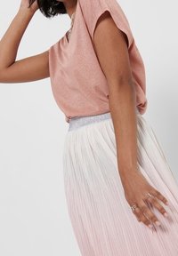 Top corto de color rosa pálido con un brillo sutil, combinado con una falda plisada que se desvanece de blanco a rosa claro, acentuada con una cinturilla plateada.