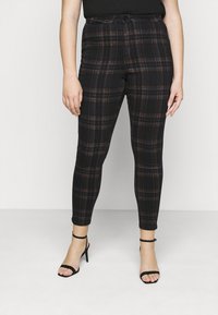 Mustat ruudulliset housut, joissa on punaisia ja sinisiä yksityiskohtia, kapeneva malli, korkea vyötärö ja nappikiinnitys, yhdistettynä mustiin remmi-korkokengiin.