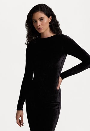 Zwarte fluwelen jurk met lange mouwen, een aangesloten silhouet en ronde halslijn. Gladde textuur, minimale details, die een strakke uitstraling toont.