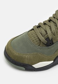 Olivově zelené semišové a síťované tenisky s texturovanými akcenty, plochými tkaničkami a gumovou podrážkou s černo-bílými detailem.