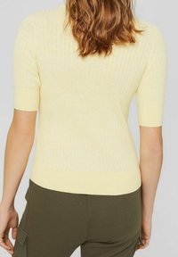 Yellow ribbed knit top with a fitted silhouette and short sleeves. Soft texture, solid color, and a contrasting hem.