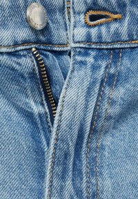 Hellblauer Denim-Reißverschluss mit kupferfarbenen Beschlägen, ausgestattet mit beiger Naht und einem Knopfverschluss. Nahaufnahme des Reißverschlusses.