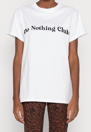 Camiseta blanca de algodón con un diseño de texto curvado negro "Do Nothing Club" en el pecho, de corte relajado y mangas cortas.