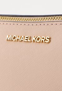 Materiale testurizzato rosa chiaro con logo "MICHAEL KORS" in tonalità oro. La cerniera è dorata e ha una finitura liscia.