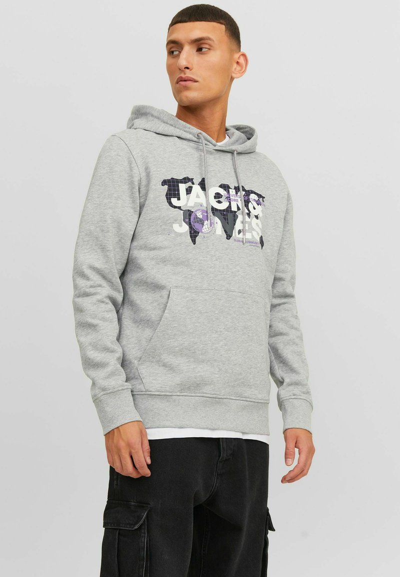 Sudadera gris con un diseño gráfico que incluye el texto "JACK & JONES" y un patrón de mapa del mundo. El look se completa con un bolsillo tipo canguro y puños acanalados.