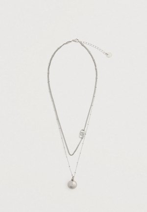 Ezüst rétegelt nyaklánc, két lánccal; az egyik sima, a másik gyöngyös, kerek medállal és csattal, amelyen hosszabbító lánc található.