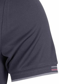 Camiseta atlética de color azul marino con una tela texturizada. Presenta un dobladillo gris y tres rayas horizontales en rojo, blanco y azul en la manga.