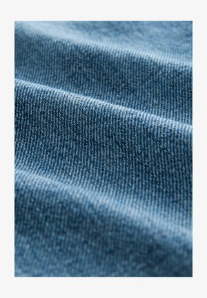 Sinine denimkangas näitab lähedalt kootud tekstuuri kerge slubiga. Omab nähtavaid horisontaalseid jooni ja peenet varjundit.