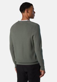Maglione a maglia verde scuro con collo a giro, maniche lunghe e orlo a coste. Presenta una texture liscia e sottili dettagli nella cucitura delle spalle.