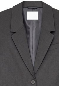 Pilkas pritaikytas bleizeris su aštriu atvartu, viena mygtuko uždarymu ir struktūruota medžiaga. Vidus lygus, su išskirtiniu prekės ženklo etiketė.