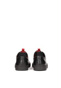 Zapatos de cuero negro con patrón embossado, forro interior rojo y suela de goma. Presentan una lengüeta trasera para facilitar su uso.