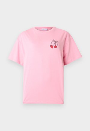 T-shirt rose à manches courtes avec un petit motif de deux lèvres rouges nouées par un ruban noir sur le haut gauche de la poitrine.