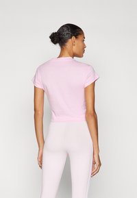 Pink cropped t-shirt with short sleeves, made of cotton. Simple design with a round neckline, smooth texture, and a fitted silhouette.