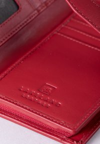 Red leather wallet interior with textured finish, featuring cardholder slots and embossed logo for Lakeland Leather.