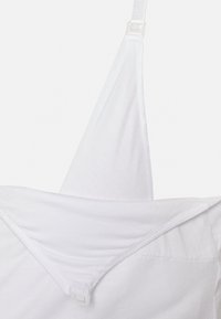 Camisola de algodão branca com alças ajustáveis, apresentando um design triangular e uma textura suave; inclui um fecho de gancho e olho nas costas.