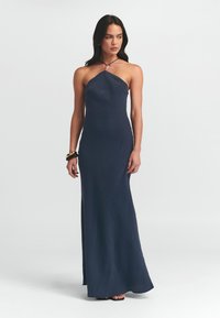 Navyblaues, bodenlanges Kleid mit Halterneck-Design, das mit einem Perlendetail am Ausschnitt sowie einem Seitenschlitz für mehr Bewegung versehen ist.