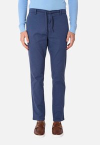 Chinos blu navy realizzati in tessuto misto cotone, con vestibilità rilassata, vita con cordino e tasche laterali, abbinati a scarpe slip-on marroni.