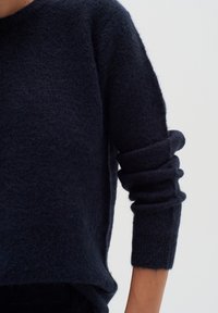 Tumedast sinisest l�õngast kootud sviiter, millel on pehme ja puhv tekstuur. Omab ümarat kaelaauku ja volditud varrukaotsi, rõhutades lõdva viimistluse.
