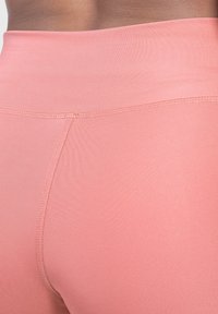 Leggings rosa a vita alta realizzati in tessuto elasticizzato; texture liscia, con design senza cuciture e dettagli di cucitura discreti lungo l'elastico in vita.