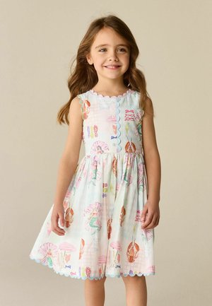 Noor tüdruk, kellel on pikad pruunid juuksed, kannab varrukateta pastelltooni kleiti, mis on kaunistatud merekarpide, homaaride ja merineitsi illustratsioonidega.