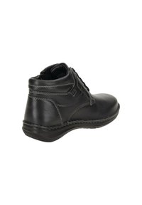 Botín de piel negra hasta el tobillo con puntera redondeada, diseño de cordones, detalle de costura elevada y suela de goma texturizada.