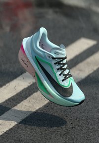 Scarpa da corsa Nike Zoom Fly con tomaia azzurra chiara, logo Swoosh nero, dettagli verdi e suola rosa con finitura testurizzata.