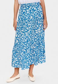 Fustă cu un model floral albastru, cu talie gathered, tiv în straturi și material ușor. Purta o bluză albă și era asortată cu pantofi bej.