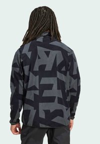 Fleecejacke in Schwarz und Grau mit einem geometrischen Muster. Hoher Kragen und lange Ärmel, mit einer lässigen Passform. Weiche Textur.