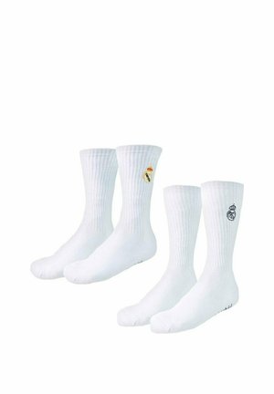 Dwie pary białych skarpet sportowych z haftowanym logo klubu piłkarskiego Real Madrid u góry.