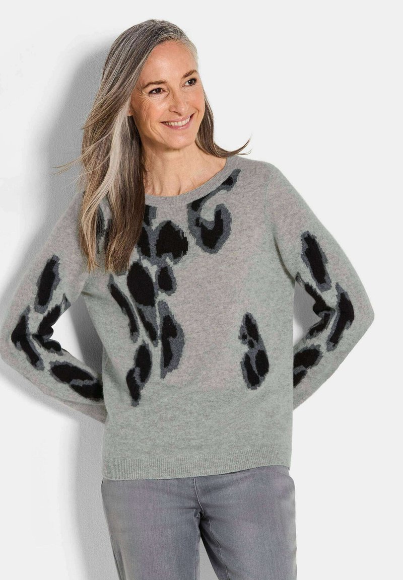 Maglione grigio in lana con macchie leopardate nere. Collo rotondo, maniche lunghe, texture morbida e orlo a coste. Abbinato a pantaloni grigio chiaro.