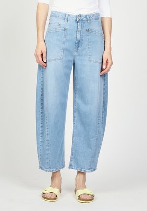 Lyseblå vide cropped jeans med store forlommer, båret med blege gule åbne tå-sandaler og en hvid langærmet top.
