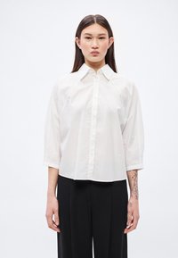 Λευκό πουκάμισο με κουμπιά, με διαχυτό γιακά και μανίκια τριών τετάρτων, με ελαφρώς άνετη εφαρμογή και απαλή βαμβακερή υφή.