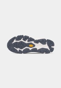 Semelle de chaussure de trail running avec une gomme noire et grise robuste et texturée, comportant un patch de logo jaune. Motif de traction courbé et multidirectionnel.