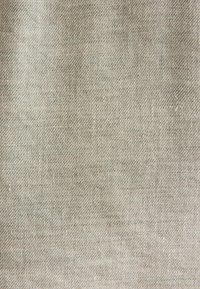 Beżowa tkanina z ukośnym splotem skośnym, ukazująca fakturowaną powierzchnię i subtelne odcieniowe różnice w nitkach.