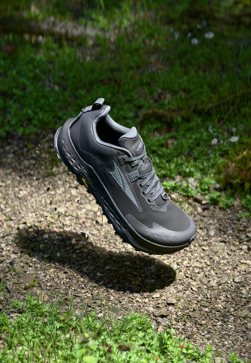 Gray athletic shoes with mesh upper, padded collar, and gray laces. Features a supportive sole and Vibram outsole for traction.