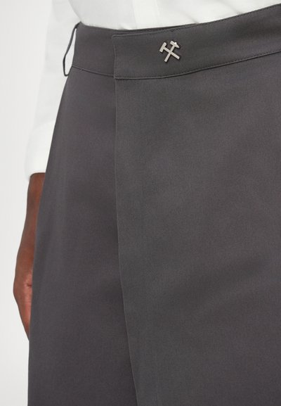 Pantalons gris ajustés avec une texture lisse, présentant un devant plat, un accent métallique décoratif au niveau de la taille, et de subtils détails de couture.