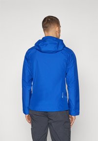 Blå vattentät jacka med huva, med en slät yta och justerbara cuffs. Inkluderar en liten logotyp vid fållen och en ventil på baksidan.