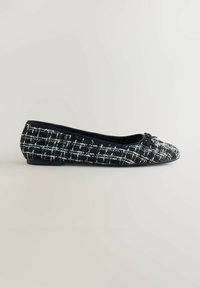 Balerini din tweed alb-negru cu vârf rotund, accent decorativ sub formă de fundiță și talpă flexibilă. Materialul texturat prezintă un model în carouri.
