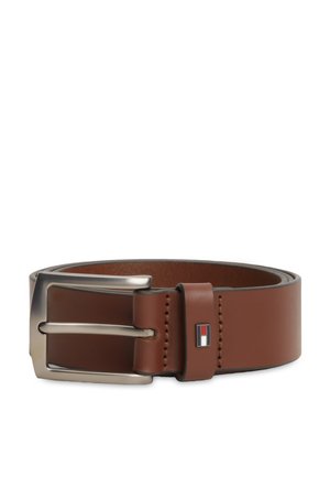 Καφέ δερμάτινη ζώνη με ασημένια μεταλλική αγκράφα και μικρό ορθογώνιο έμβλημα με κόκκινα, λευκά και μαύρα χρώματα στο λουράκι της ζώνης.