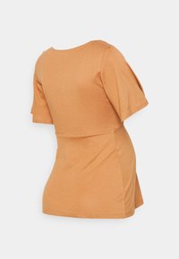 Top justo de manga curta em algodão na cor laranja clara. Apresenta um decote redondo e uma bainha ligeiramente evasé nas costas. Textura suave.