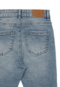 Jeans in denim blu chiaro con una texture leggermente sbiadita, dotati di due tasche posteriori e una patch in pelle marrone sulla cintura.